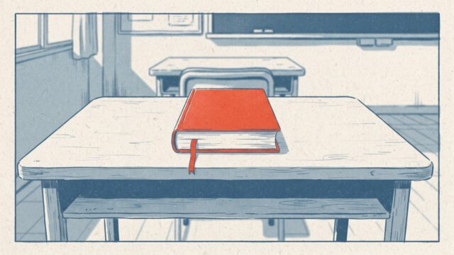 教室の生徒の机の上に、朱色の新しい本が閉じたまま置かれ、しおり紐が垂れているイラスト